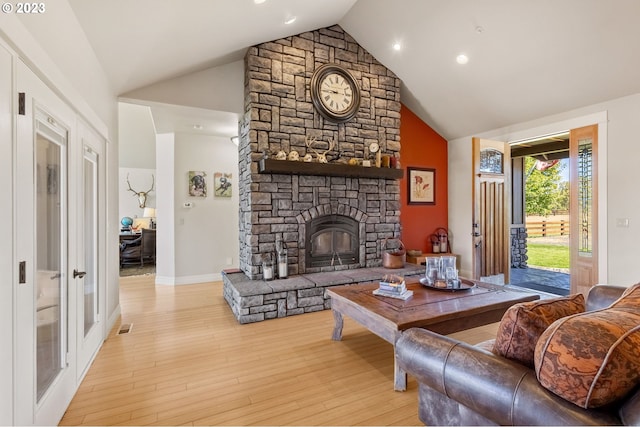 living room with a stone fireplace, high vaulted ceiling, and light hardwood / wood-style flooring