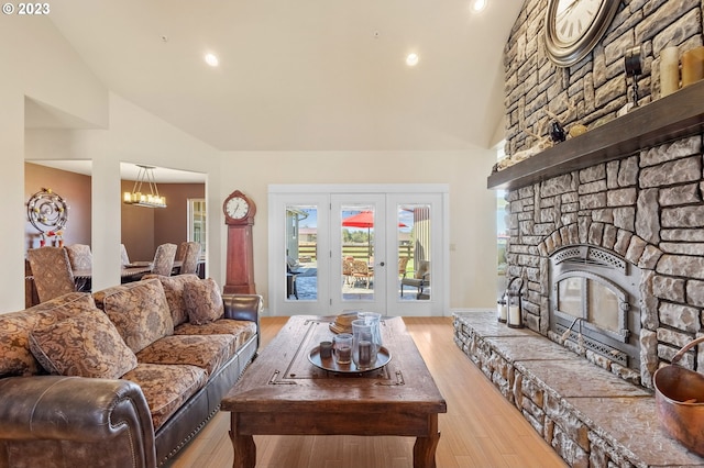 living room featuring a chandelier, light hardwood / wood-style flooring, high vaulted ceiling, and a fireplace