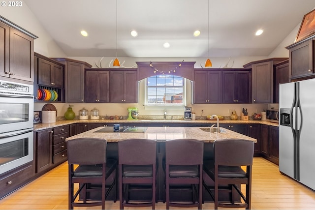 kitchen featuring a kitchen island with sink, stainless steel appliances, and vaulted ceiling