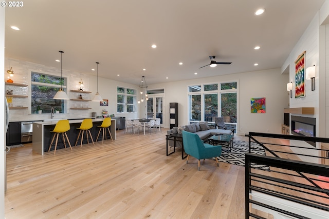 living room featuring light hardwood / wood-style flooring, ceiling fan, and sink