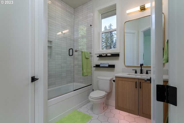 full bathroom with tile floors, bath / shower combo with glass door, vanity with extensive cabinet space, and toilet