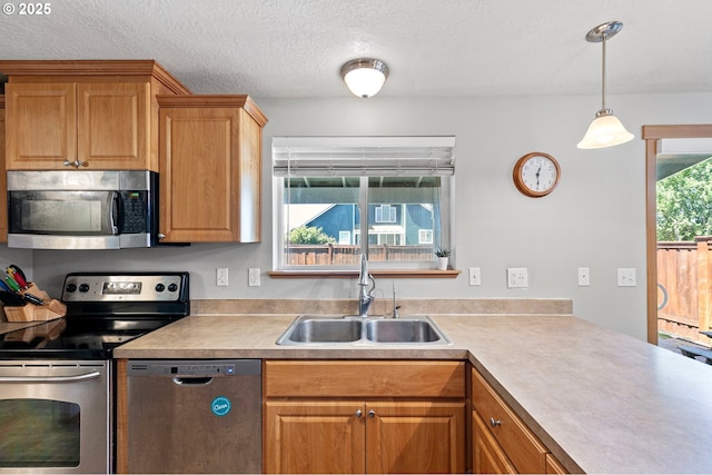 1062 Applegate Pl, Harrisburg, OR 97446 - kitchen with stainless steel appliances, a sink, light countertops, pendant lighting, and a textured ceiling