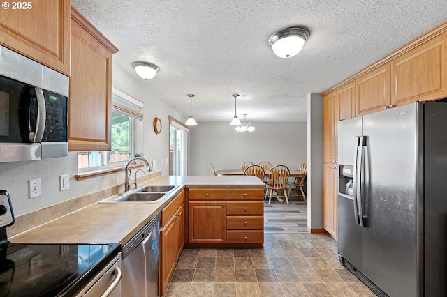 1062 Applegate Pl, Harrisburg, OR 97446 - kitchen with stainless steel appliances, a sink, a peninsula, a textured ceiling, and decorative light fixtures