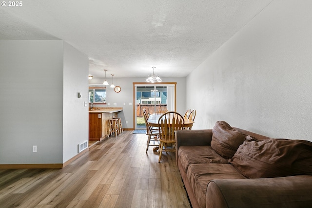 1062 Applegate Pl, Harrisburg, OR 97446 - living area with a chandelier, light wood-style flooring, a textured ceiling, and baseboards