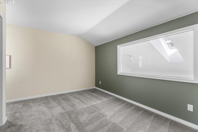 carpeted empty room with vaulted ceiling with skylight and baseboards