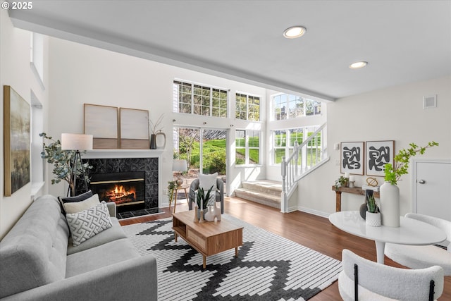 living room featuring recessed lighting, wood finished floors, visible vents, a premium fireplace, and baseboards