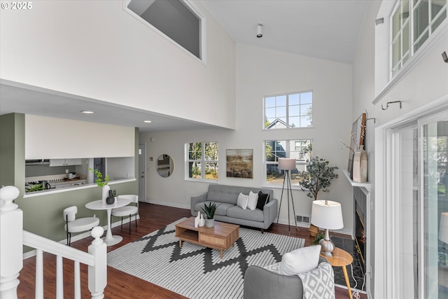 living room featuring high vaulted ceiling, baseboards, wood finished floors, and visible vents