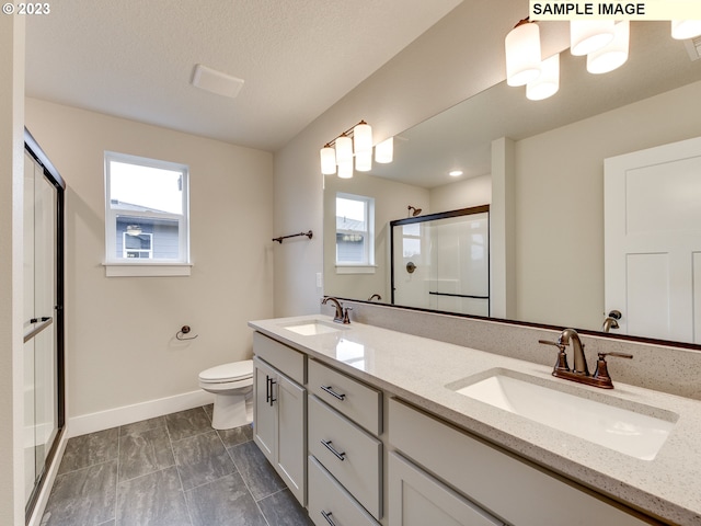 bathroom featuring toilet, a shower with door, dual sinks, tile flooring, and oversized vanity