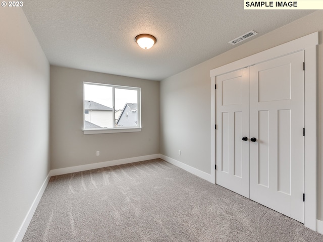 carpeted empty room featuring a textured ceiling