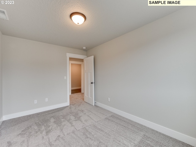 carpeted empty room featuring a textured ceiling