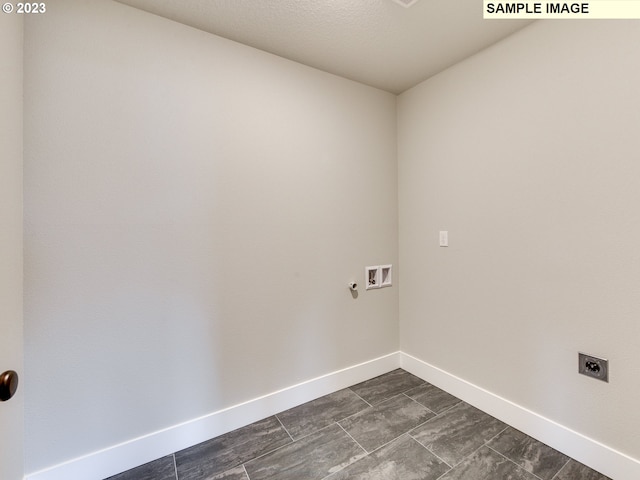 clothes washing area with electric dryer hookup, washer hookup, and dark tile flooring