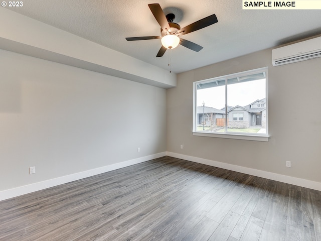 empty room featuring a textured ceiling, ceiling fan, dark wood-type flooring, and an AC wall unit