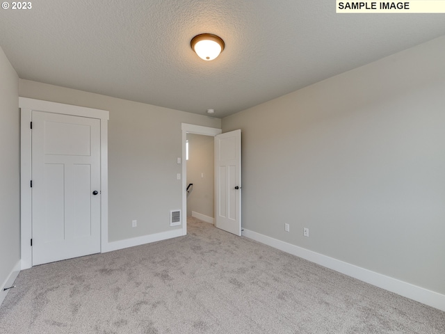 carpeted empty room featuring a textured ceiling