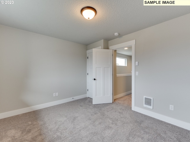 unfurnished bedroom with light colored carpet and a textured ceiling