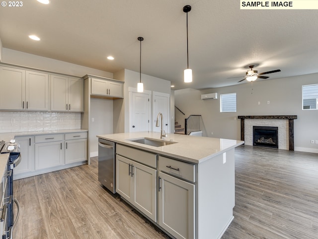 kitchen featuring ceiling fan, sink, dishwasher, a center island with sink, and light hardwood / wood-style floors