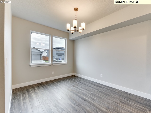 spare room with dark hardwood / wood-style floors and an inviting chandelier