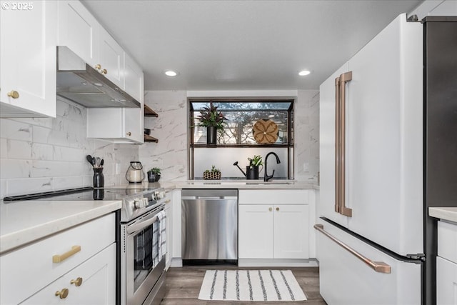 kitchen with a sink, stainless steel appliances, light countertops, under cabinet range hood, and white cabinetry