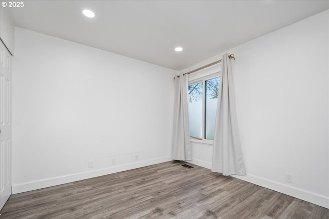 unfurnished room with visible vents, recessed lighting, wood finished floors, and baseboards