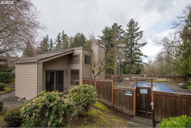 view of side of home featuring a chimney, a wooden deck, and fence