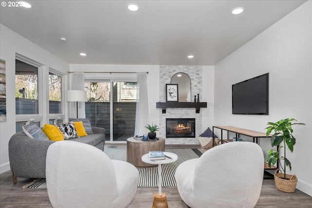 living area with recessed lighting, a brick fireplace, and wood finished floors