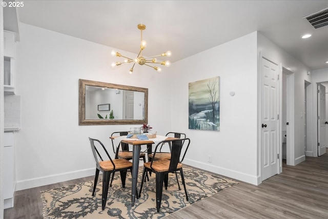 dining space featuring visible vents, baseboards, a notable chandelier, and wood finished floors