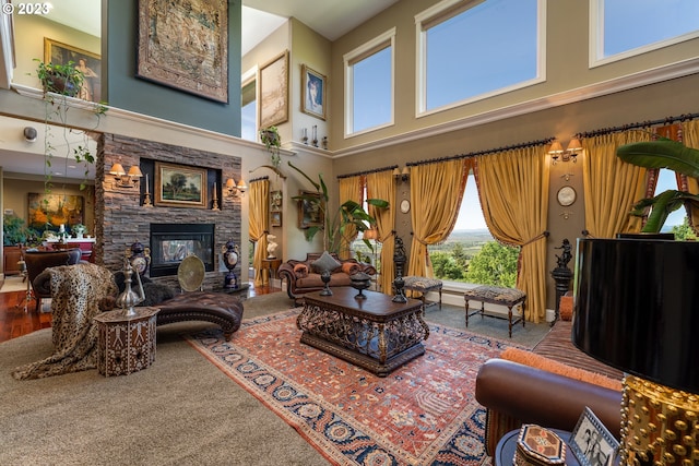 carpeted living room with a stone fireplace and a high ceiling