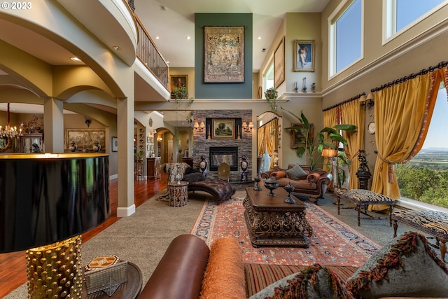 interior space featuring a high ceiling, a stone fireplace, and hardwood / wood-style flooring