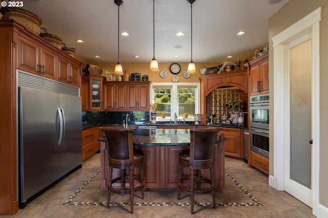 kitchen featuring light tile floors, a center island with sink, backsplash, and stainless steel appliances