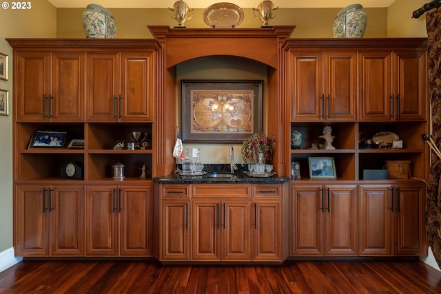 kitchen with dark stone counters, dark hardwood / wood-style flooring, and sink