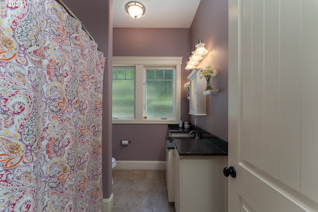 bathroom with toilet, vanity, and tile flooring