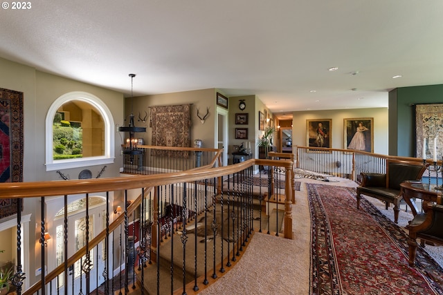 corridor featuring carpet flooring and a notable chandelier