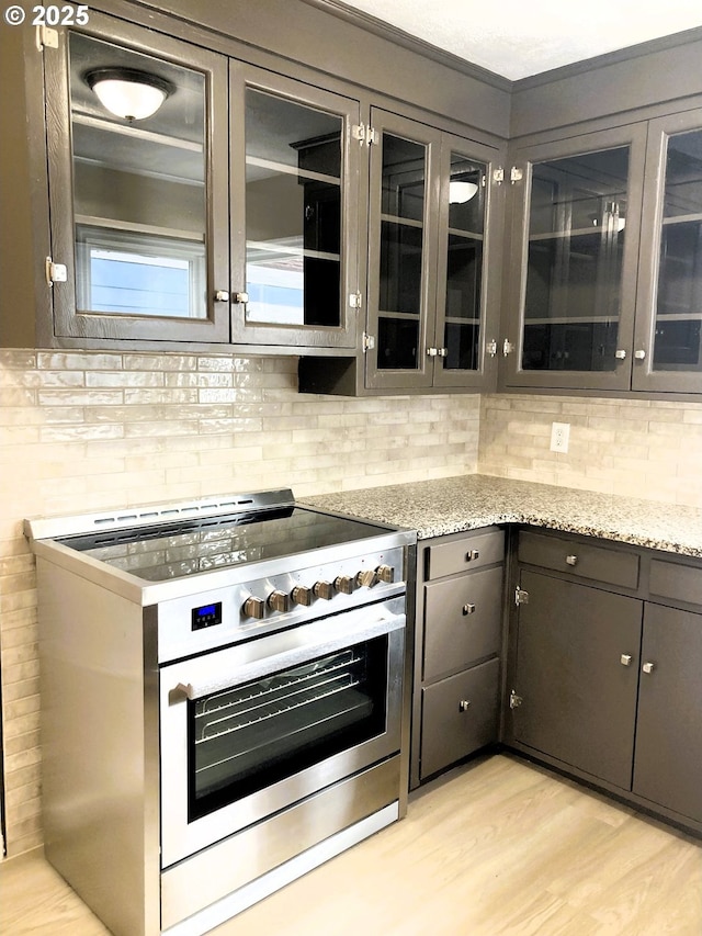 703 Cowlitz Way, Kelso, WA 98626 - kitchen featuring stainless steel range, decorative backsplash, glass insert cabinets, and light wood-type flooring