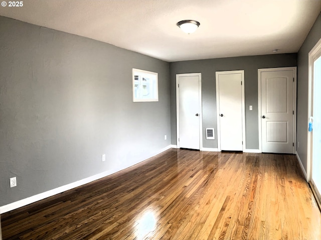 703 Cowlitz Way, Kelso, WA 98626 - unfurnished bedroom featuring two closets, wood finished floors, heating unit, and multiple windows