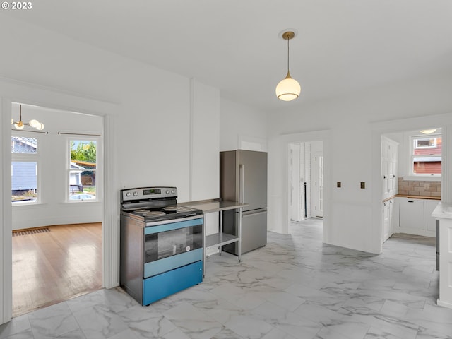 kitchen featuring white cabinets, pendant lighting, stainless steel appliances, and light tile floors