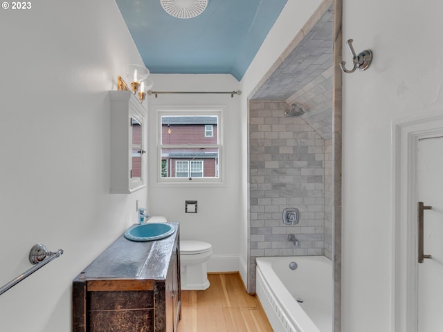 full bathroom featuring tiled shower / bath combo, oversized vanity, toilet, and hardwood / wood-style flooring