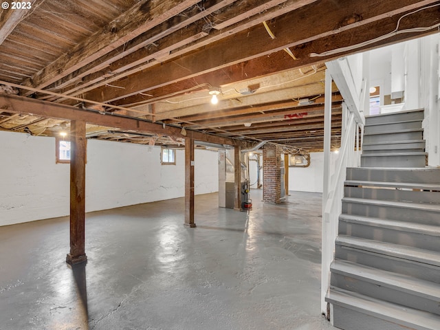 basement featuring plenty of natural light, brick wall, and heating utilities