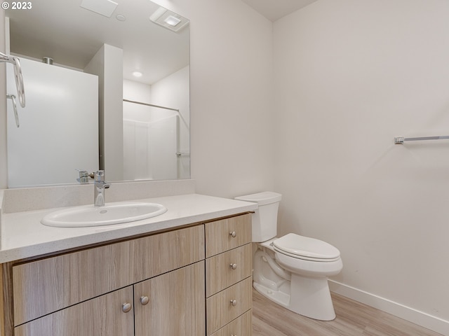 4738 SE Belmont St, Portland, OR 97215 - bathroom featuring toilet, vanity with extensive cabinet space, and hardwood / wood-style flooring