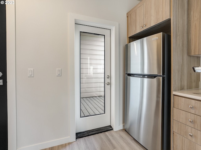 4738 SE Belmont St, Portland, OR 97215 - kitchen with stainless steel fridge, light brown cabinets, and light hardwood / wood-style flooring