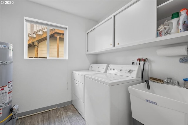 clothes washing area featuring washing machine and dryer, cabinet space, secured water heater, and light wood-style floors