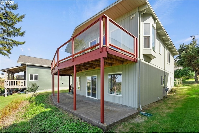 rear view of property with a yard, a deck, and a patio