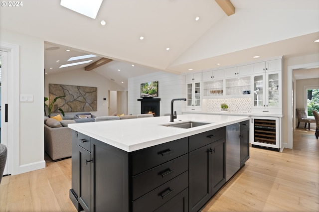 kitchen featuring a sink, a lit fireplace, beverage cooler, and a skylight