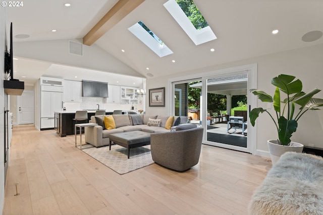 living room featuring visible vents, high vaulted ceiling, a skylight, light wood-style floors, and beamed ceiling