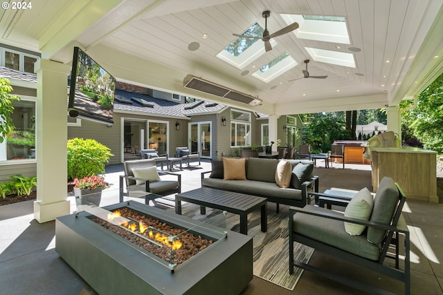 view of patio with area for grilling, a hot tub, an outdoor living space with a fire pit, and a ceiling fan