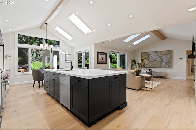 kitchen featuring open floor plan, dishwasher, light countertops, a skylight, and a sink