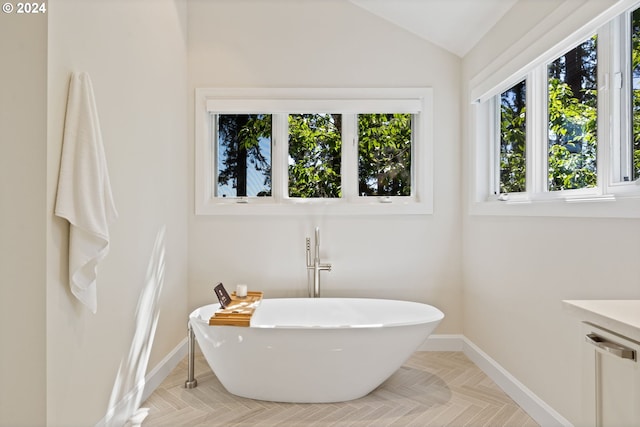 bathroom with baseboards, lofted ceiling, and a freestanding bath