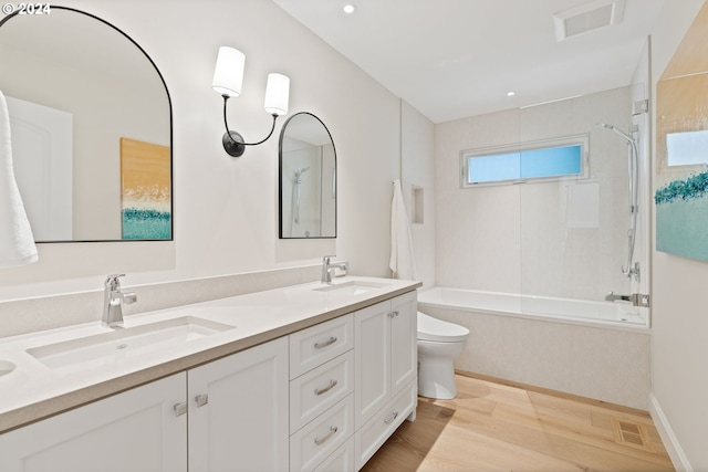 bathroom with a sink, toilet, wood finished floors, and  shower combination