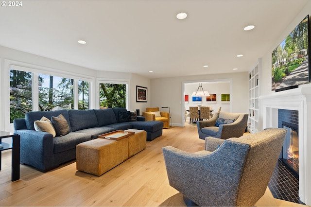 living room with a tiled fireplace, recessed lighting, and light wood-type flooring