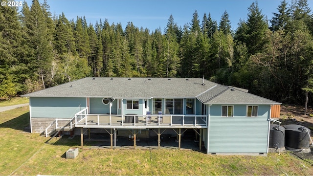 53310 Morrison Rd, Bandon, OR 97411 - back of property with a deck, roof with shingles, a lawn, and a view of trees