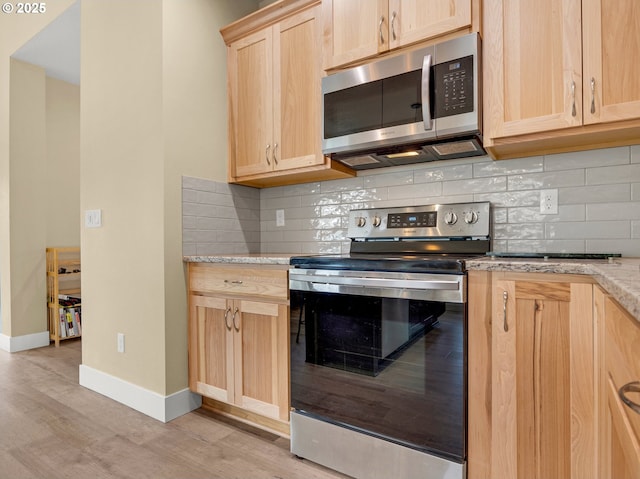 293 W Kershul Cir, Gearhart, OR 97138 - kitchen featuring appliances with stainless steel finishes, light brown cabinetry, light wood-style floors, and tasteful backsplash