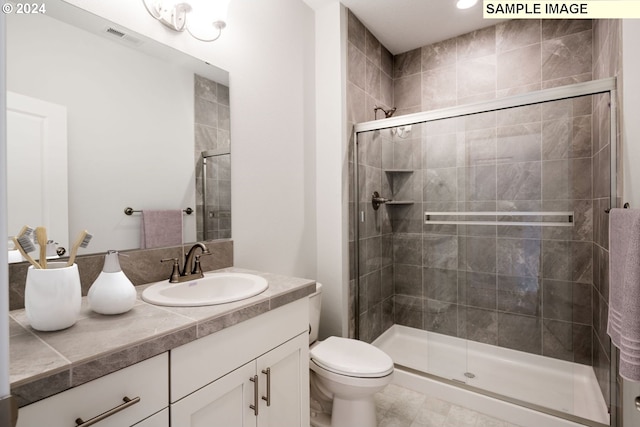 bathroom with vanity, toilet, and a shower with door